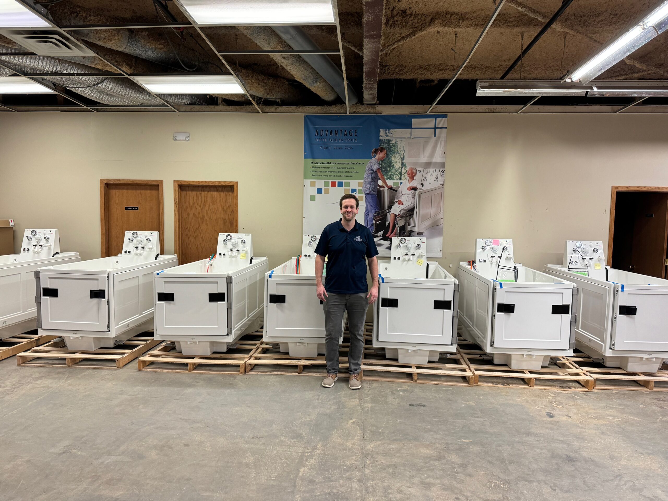 Apollo Bath team member in front of a selection of hydrotherapy tubs, senior bath solutions